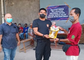 Kapolsek Sungai Gelam saat memberikan bonus 2 liter minyak goreng kepada warga yang mengikuti vaksinasi ke 3 (foto: ist)