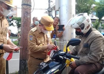 Al Haris saat memberikan bendera Merah Putih kepada pengendara yang melintas di Simpang IV Bank Indonesia (foto: ist)