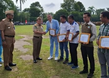 Gubernur Jambi Al Haris menyerahkan penghargaan kepada perwakilan perusahaan dalam Upacara Peringatan Bulan Keselamatan dan Kesehatan Kerja (K3) yang dirangkaikan dengan Apel Kesadaran Nasional ASN di Lapangan Kantor Gubernur Jambi, Senin (19/1/2026).