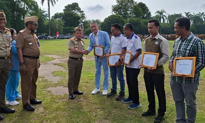 Gubernur Jambi Al Haris menyerahkan penghargaan kepada perwakilan perusahaan dalam Upacara Peringatan Bulan Keselamatan dan Kesehatan Kerja (K3) yang dirangkaikan dengan Apel Kesadaran Nasional ASN di Lapangan Kantor Gubernur Jambi, Senin (19/1/2026).